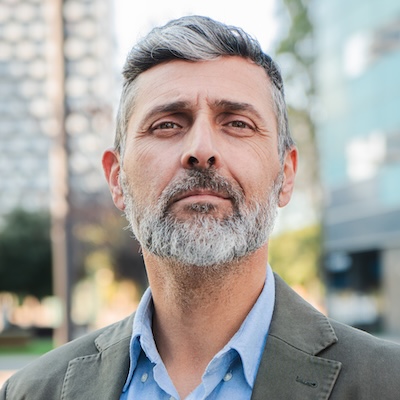 Vertical. Confident mature businessman looking at camera with a serious expression, professional man with beard in a suit jacket standing outdoors, exuding leadership and experience